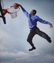Businessman playing basketball. Photographe : Mike Kemp