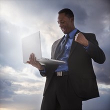 Successful businessman holding a laptop computer. Photographe : Mike Kemp