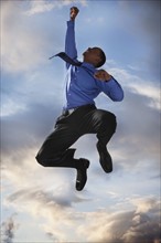 Excited businessman jumping. Photographe : Mike Kemp