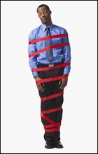 Businessman wrapped in red tape. Photographe : Mike Kemp