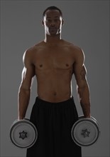 Physically fit man lifting dumbbells. Photographe : Mike Kemp