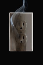 Smoke emanating from an electrical outlet. Photographe : Mike Kemp