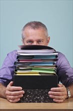 Man sitting behind a stack of paper work. Photographe : RTimages