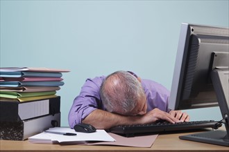 Overworked man sleeping at his desk. Photographe : RTimages