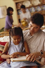 Young girl reading with her father. Photographe : Rob Lewine