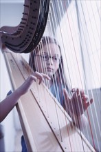 Young girl playing the harp. Photographe : Rob Lewine