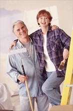 Couple painting the walls in their home. Photographe : Rob Lewine