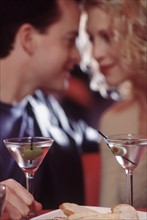 Couple drinking martinis in a restaurant. Photographe : Rob Lewine