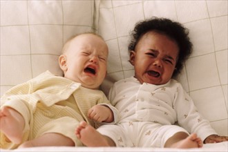 Two babies crying on a couch. Photographe : Rob Lewine