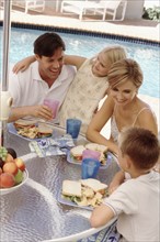 Family eating lunch by the pool. Photographe : Rob Lewine