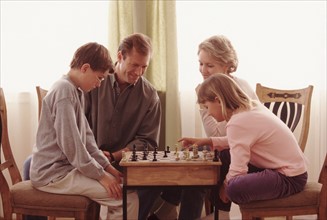 Family playing chess together. Photographe : Rob Lewine