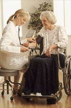 Healthcare worker checking an elderly woman's blood pressure. Photographe : Rob Lewine