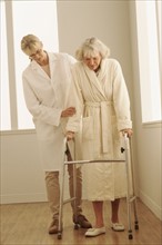 Healthcare worker helping a woman walk with a walker. Photographe : Rob Lewine
