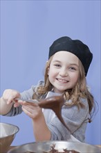 Young girl holding a mixing spoon. Photographe : Dan Bannister