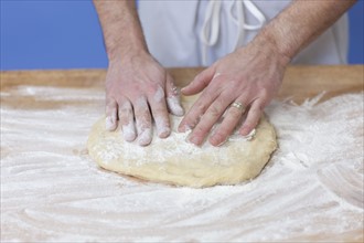 Man's hands kneading bread dough. Photographe : Dan Bannister