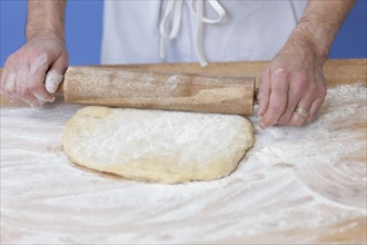 Man' hands rolling out bread dough. Photographe : Dan Bannister