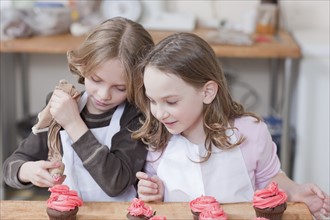 Young girls decorating cupcakes. Photographe : Dan Bannister