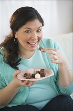 Overweight woman eating chocolates.