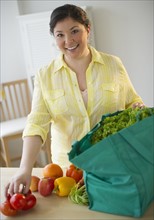 Woman unpacking vegetables from grocery bag.