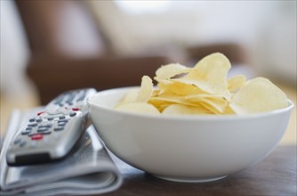 Bowl of chips beside remote control.