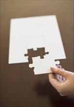 Hand putting last puzzle piece in puzzle.