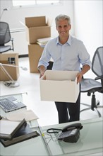 Businessman holding a box in his new office.