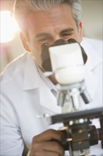Researcher looking through microscope.