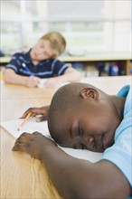 Elementary students sleeping at his desk.