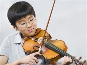 Elementary school student playing violin in music class.