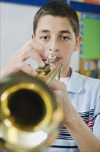 Elementary school student playing trumpet.