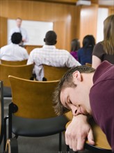 College student sleeping in lecture hall.