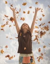 Pretty teenage girl throwing leaves in the air. Photo : Mike Kemp
