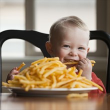 Toddler eating a large plate of French fries. Photo : Mike Kemp