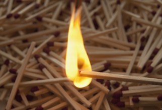 Lit match on top of a pile of wooden matches. Photo : Mike Kemp