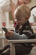 Toddler playing with cell phone. Photo : Mike Kemp