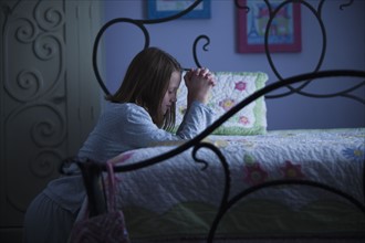Young girl praying before bed. Photo : Mike Kemp