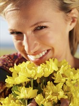 Woman holding yellow flowers. Photo : momentimages
