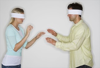 Blindfolded couple looking for each other.
