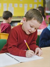Kindergarten student writing in notebook.