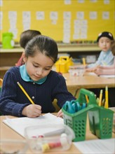 Kindergarten student writing in notebook.
