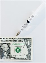 Syringe on American dollar bill. Photo : Jamie Grill