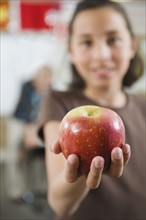 Elementary student holding an apple in her hand.