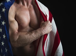 Muscular man wearing American flag as a cape. Photo : Daniel Grill