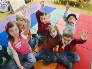 Elementary school students raising their hands.