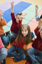 Elementary school students raising their hands.