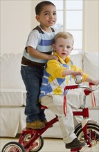 Two children on a tricycle. Photo : Chris Grill