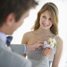 Man pinning corsage on his date's prom dress.