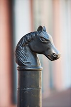Iron statue of a horse's head on top of a post.