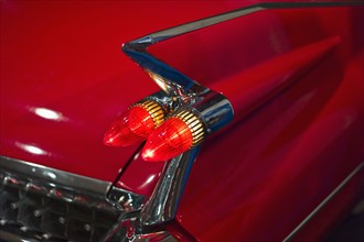 Tail fin on a 1959 red automobile.