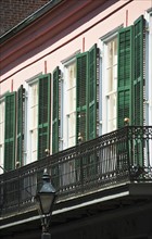 Balcony and windows with green shutters.